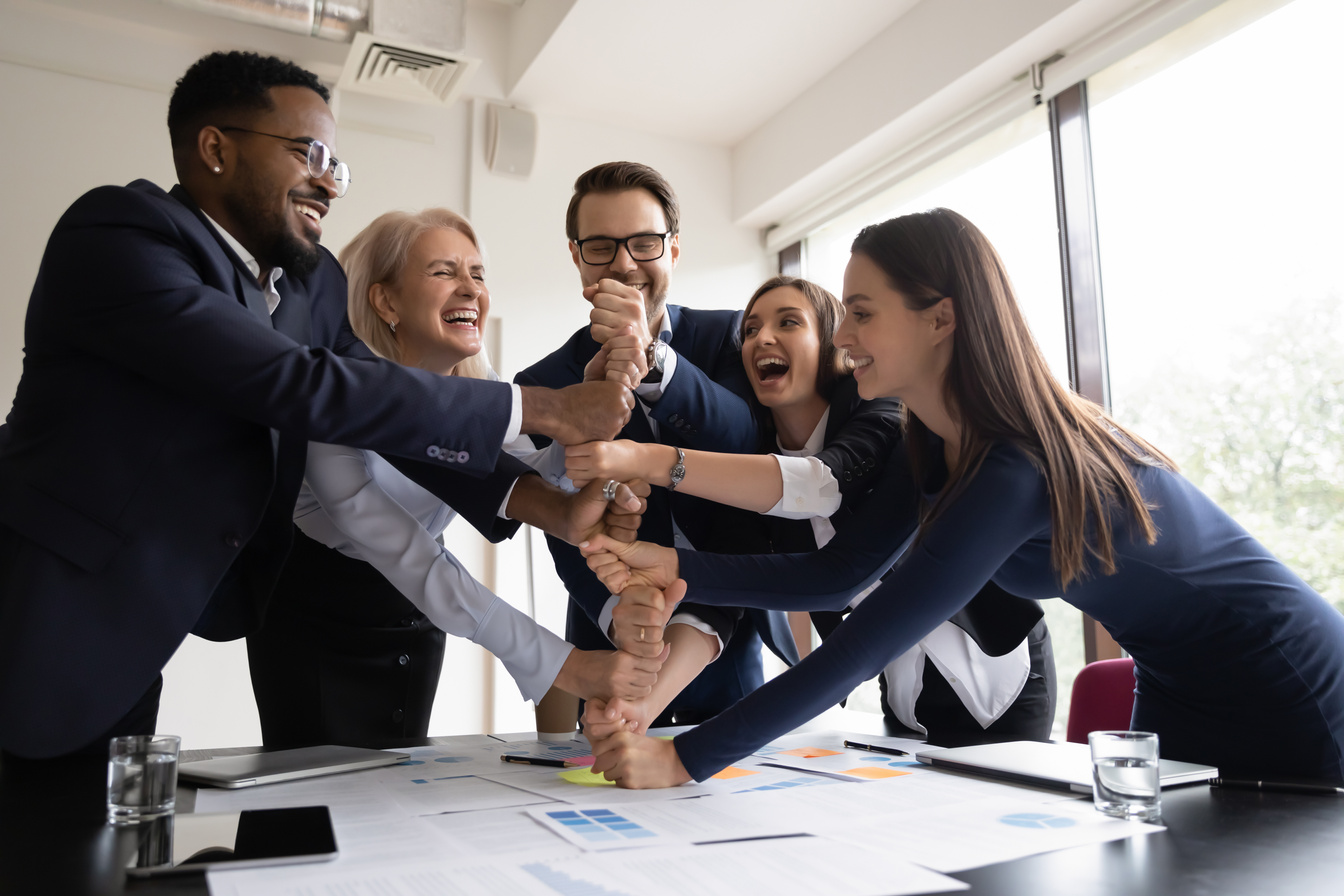 Happy employees coworkers stacking fists together showing corporate spirit